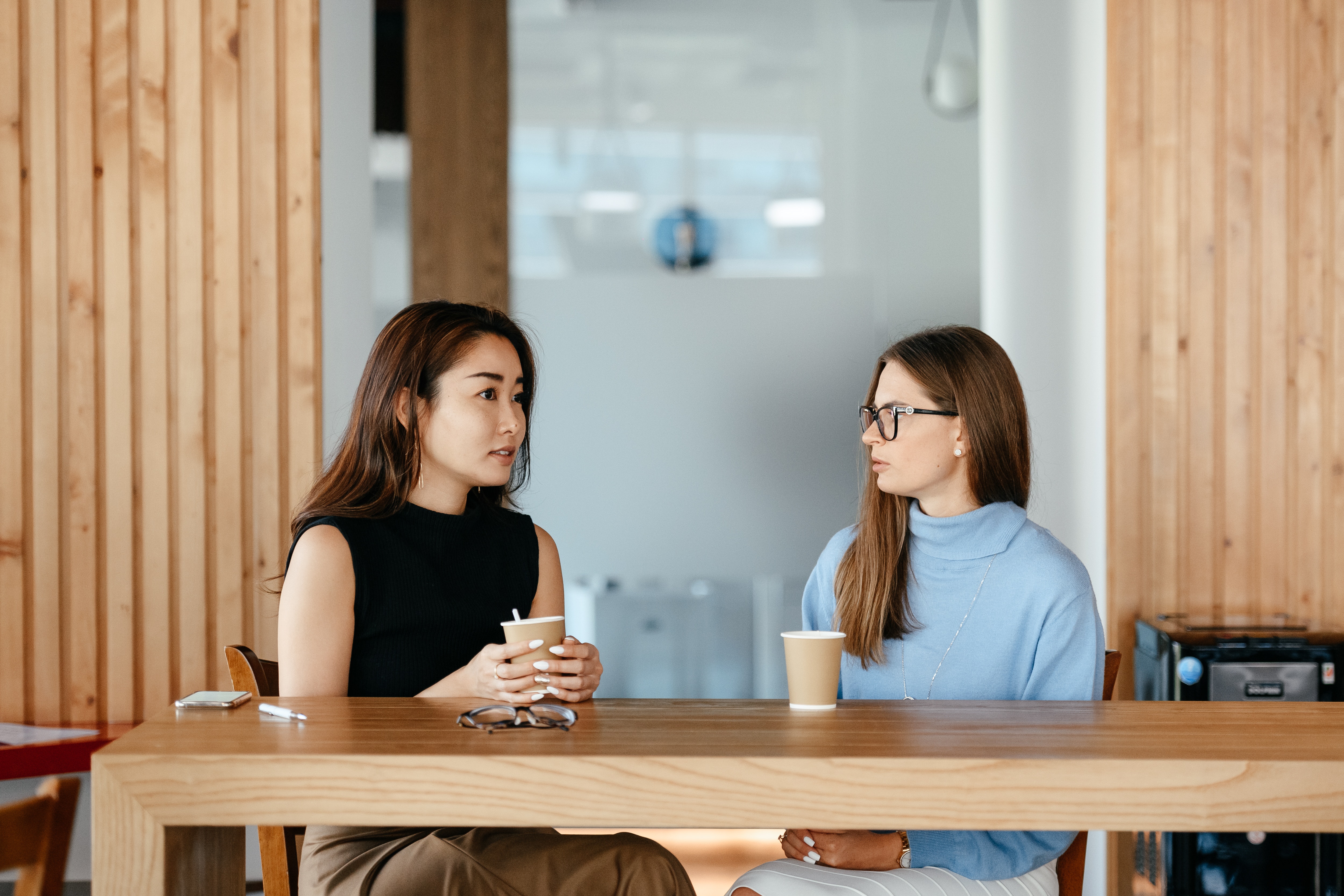 two women sitting at a table drinking coffee